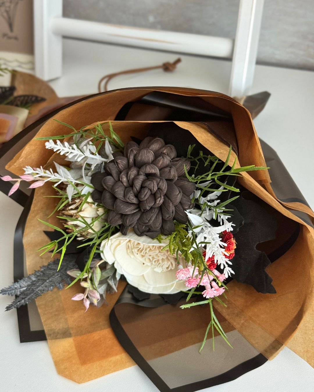 Bouquet of flowers wrapped in brown paper on a white surface