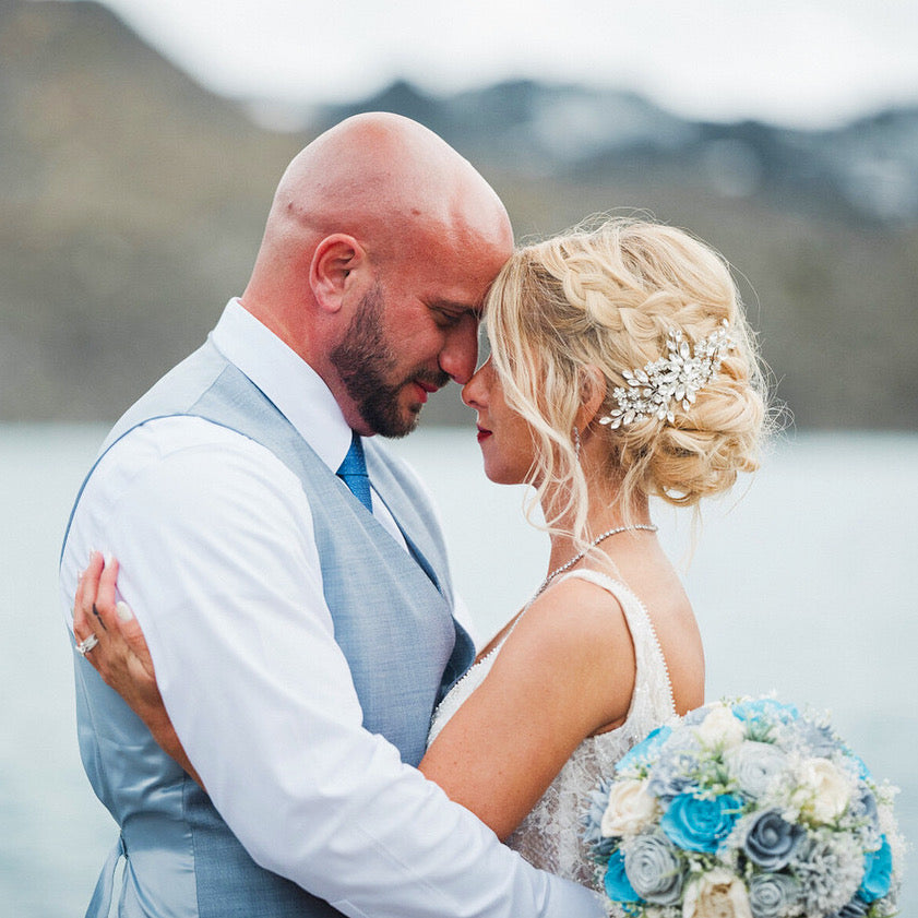 Couple embracing with a scenic background of mountains and water.