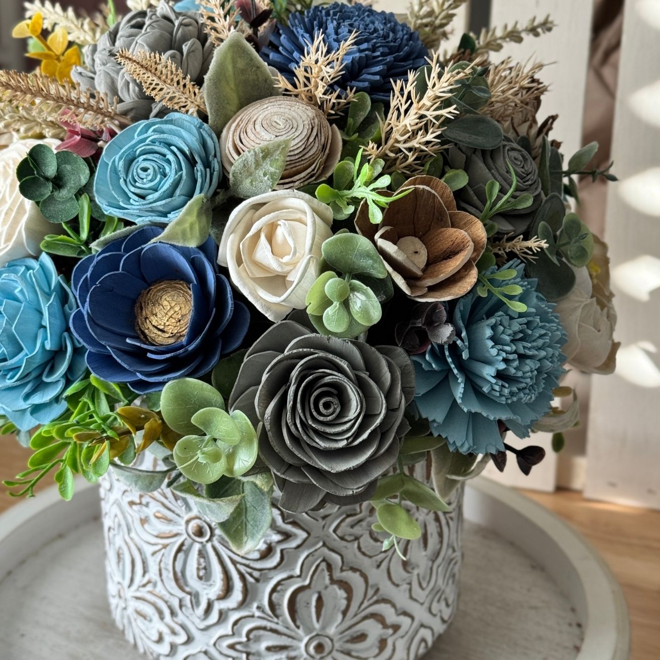 Bouquet of artificial flowers in a decorative vase on a wooden surface