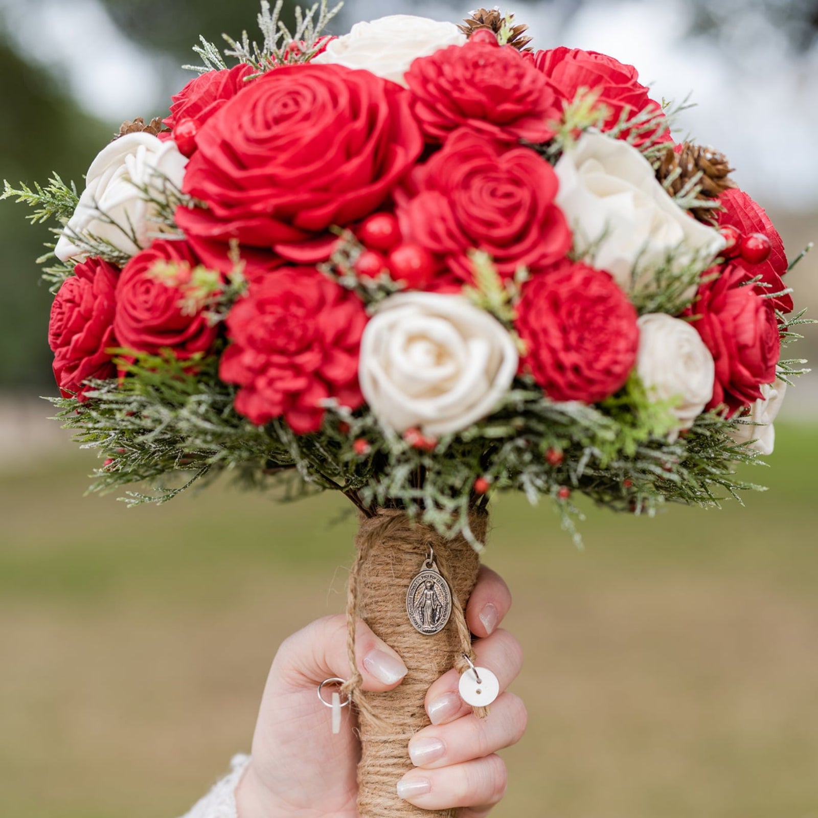 Bouquet of red and white flowers held by a hand with a blurred background