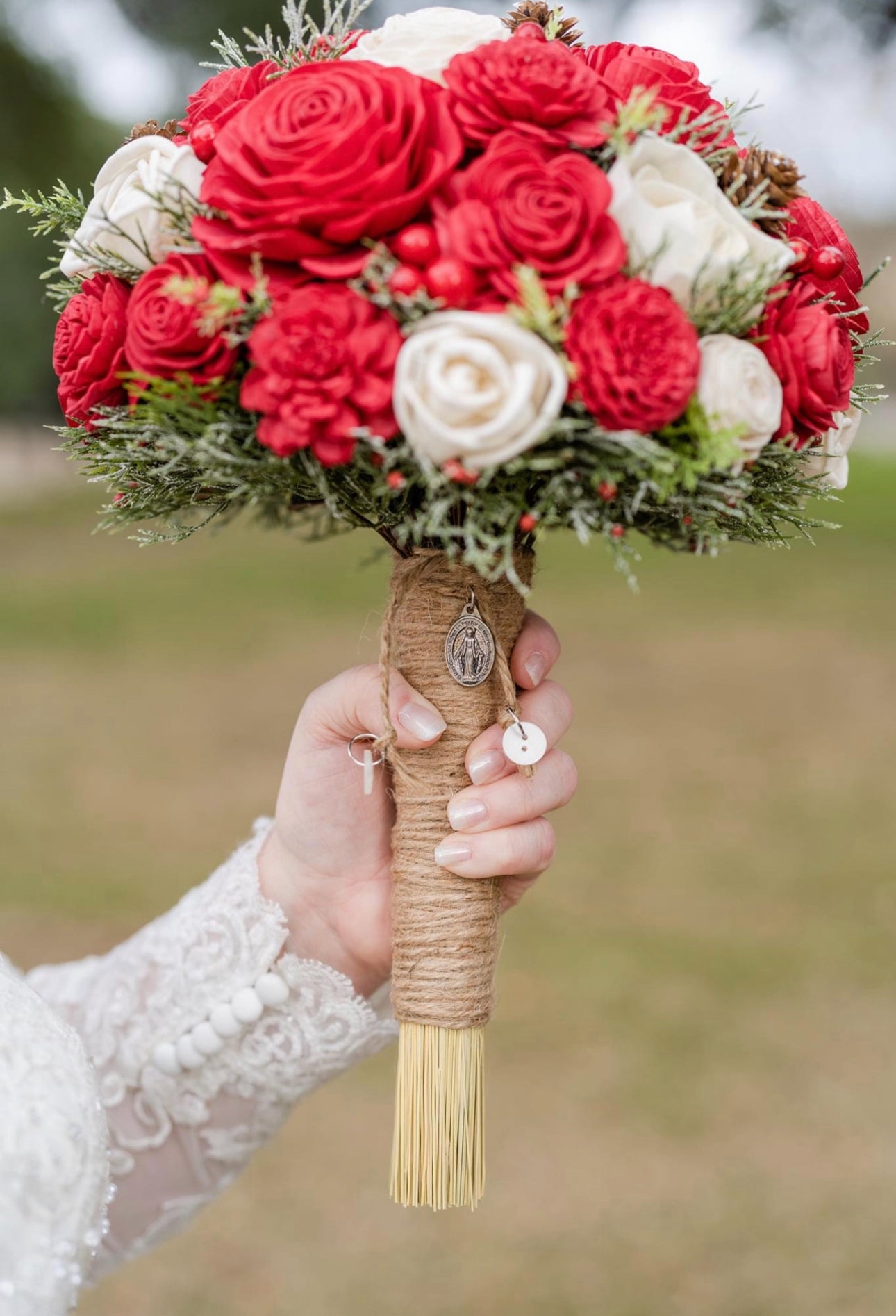 Bouquet of red and white sola wood flowers held by a hand with a blurred natural background