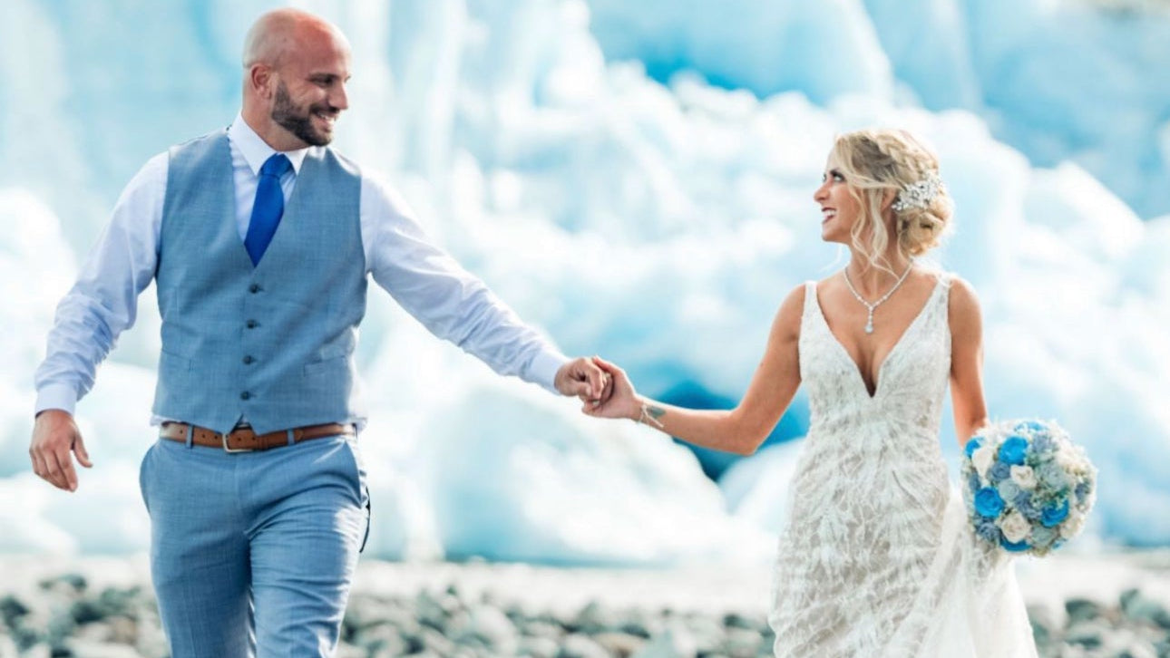 Couple holding hands in front of a glacier