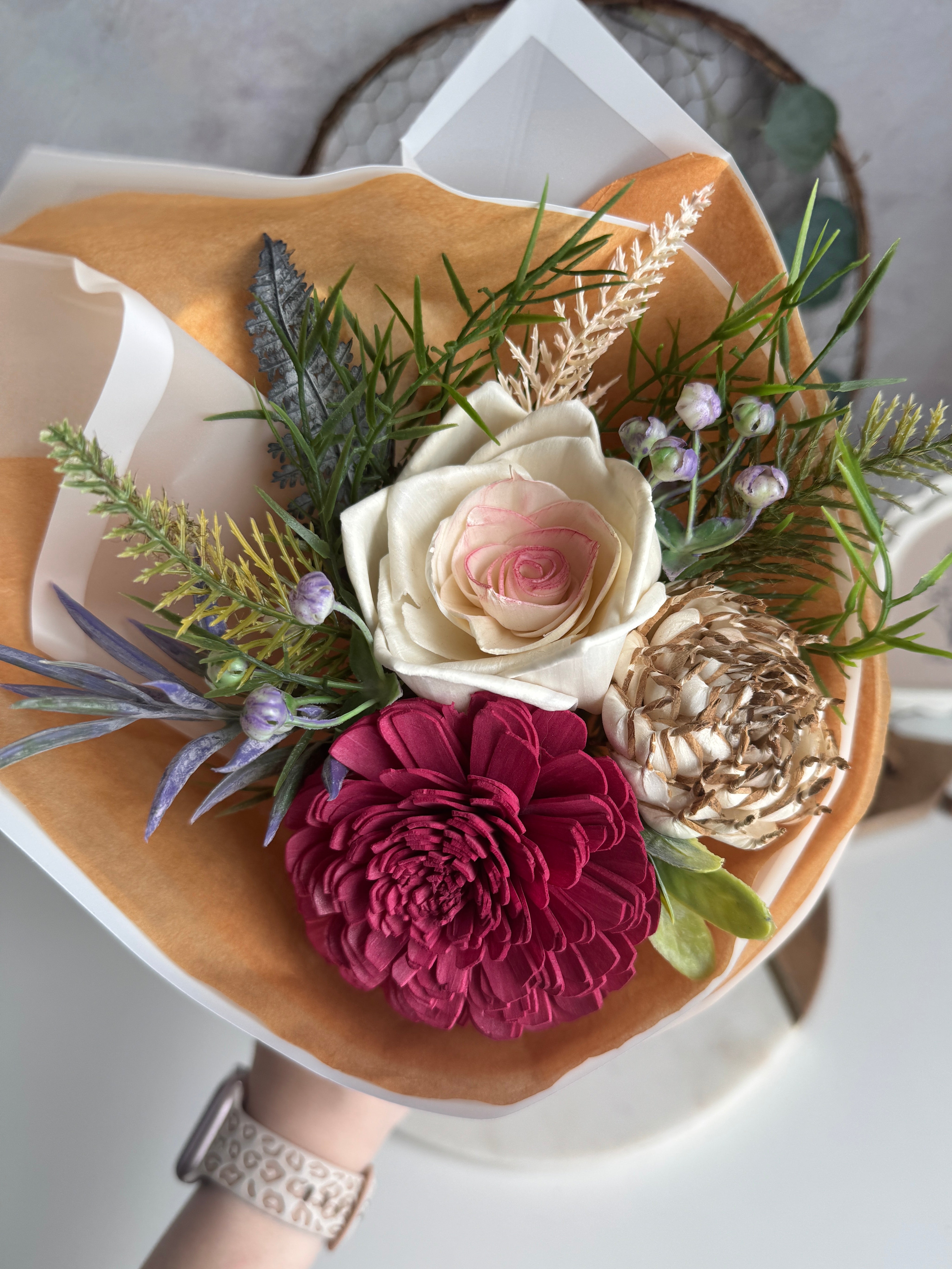 Bouquet of flowers with a focus on a white rose and a red flower, set against a blurred background.