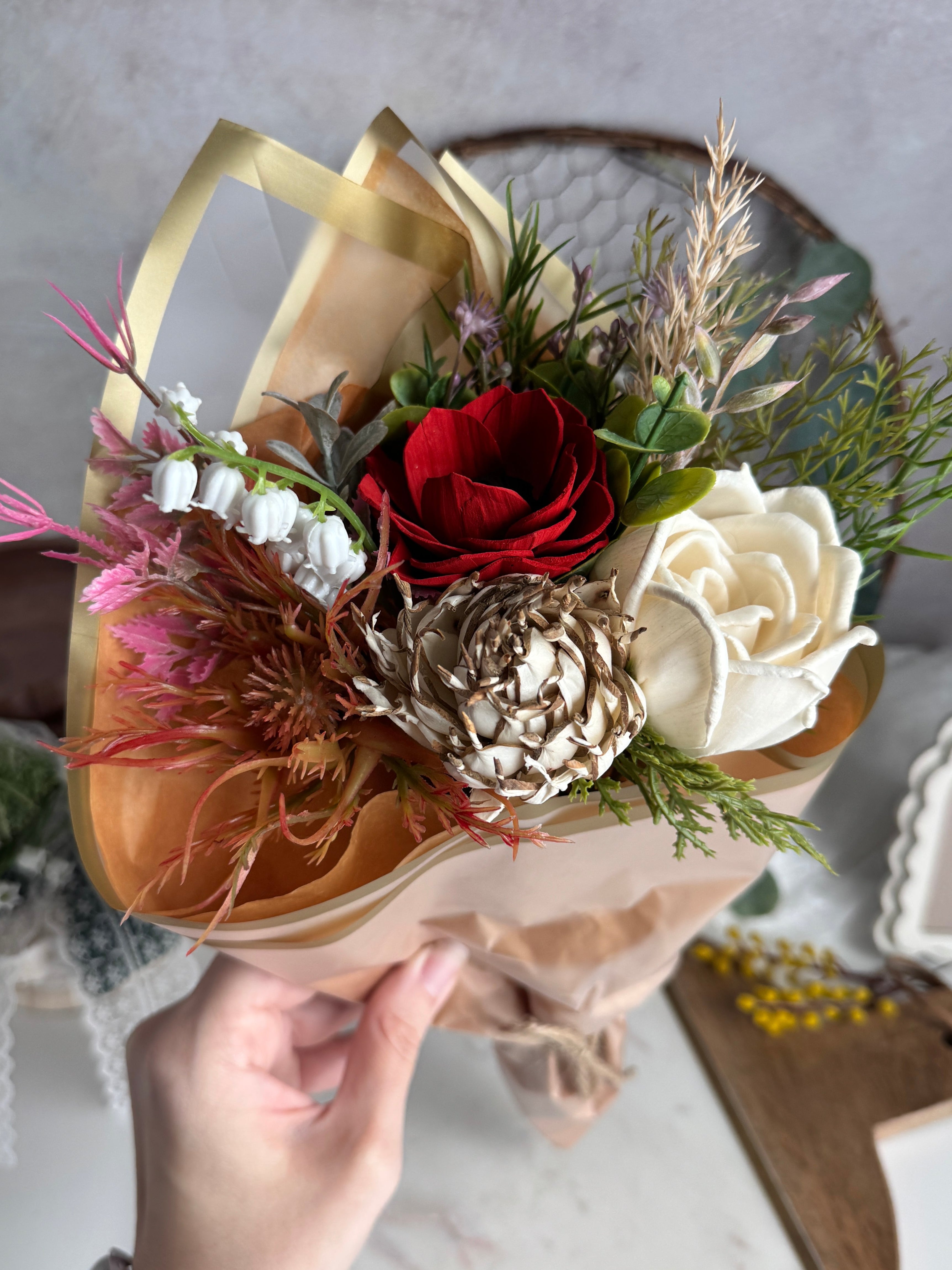 Hand holding a bouquet of flowers with a neutral background