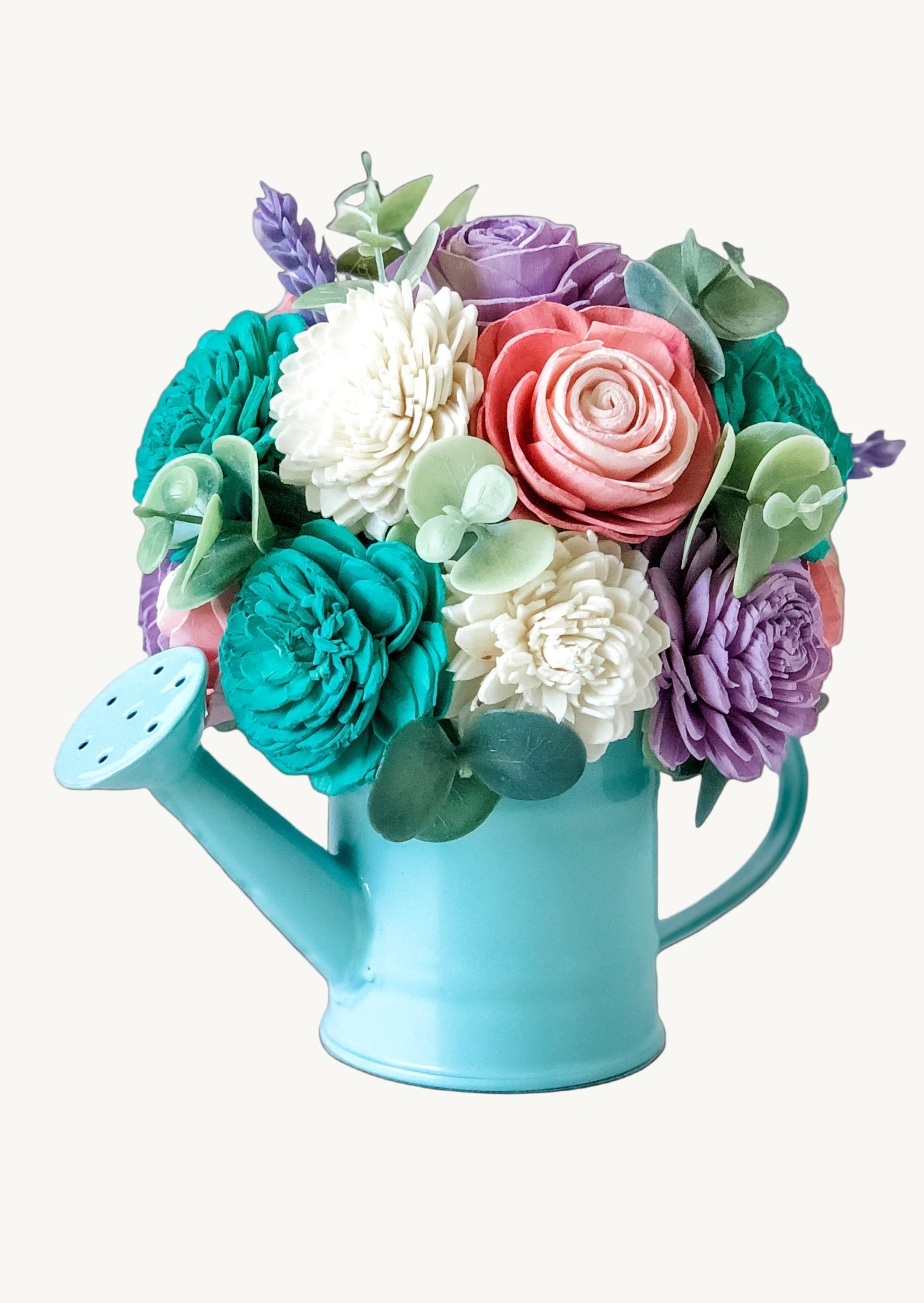 Colorful flower arrangement in a blue watering can on a white background