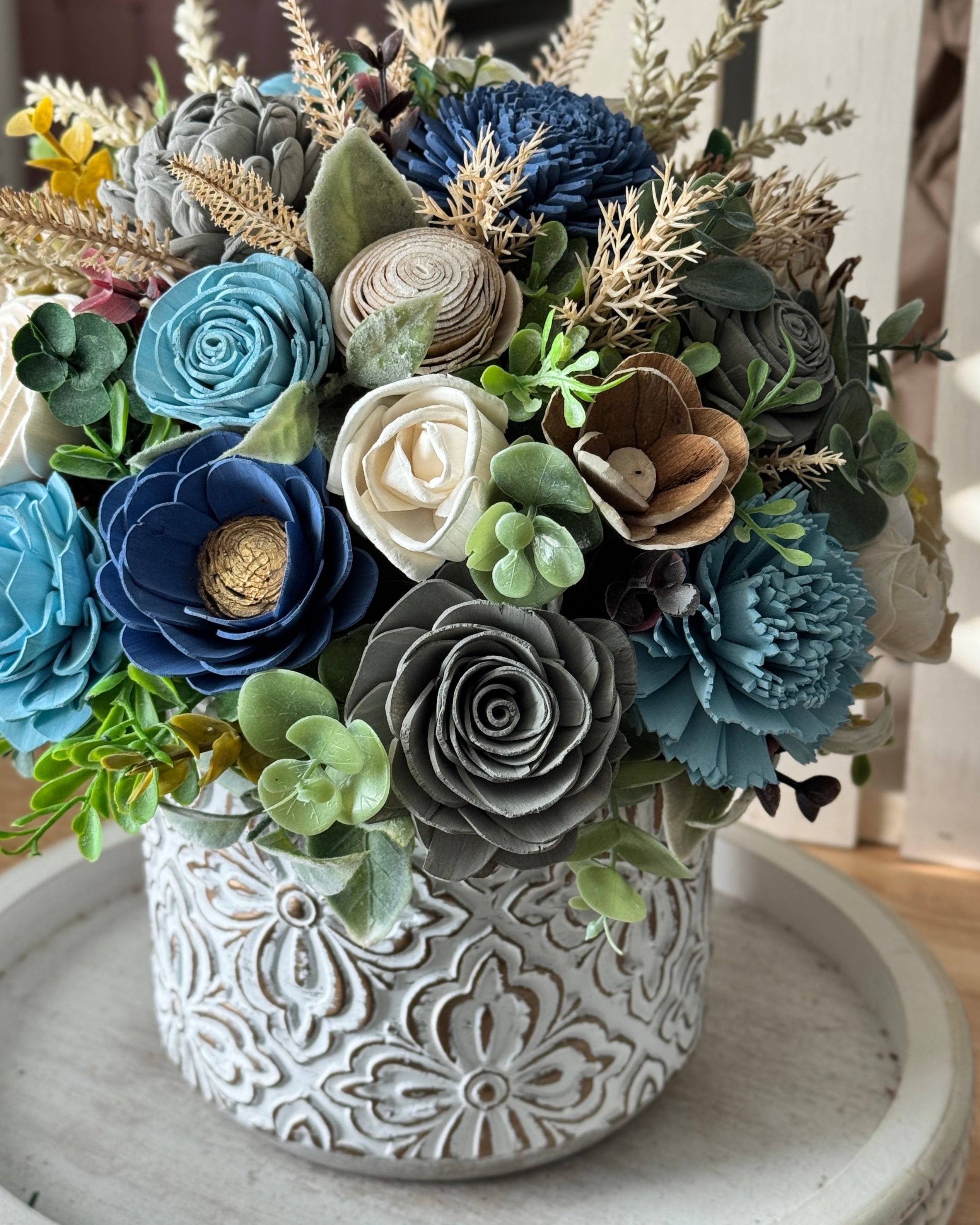 Decorative faux flower arrangement in a textured pot on a wooden surface