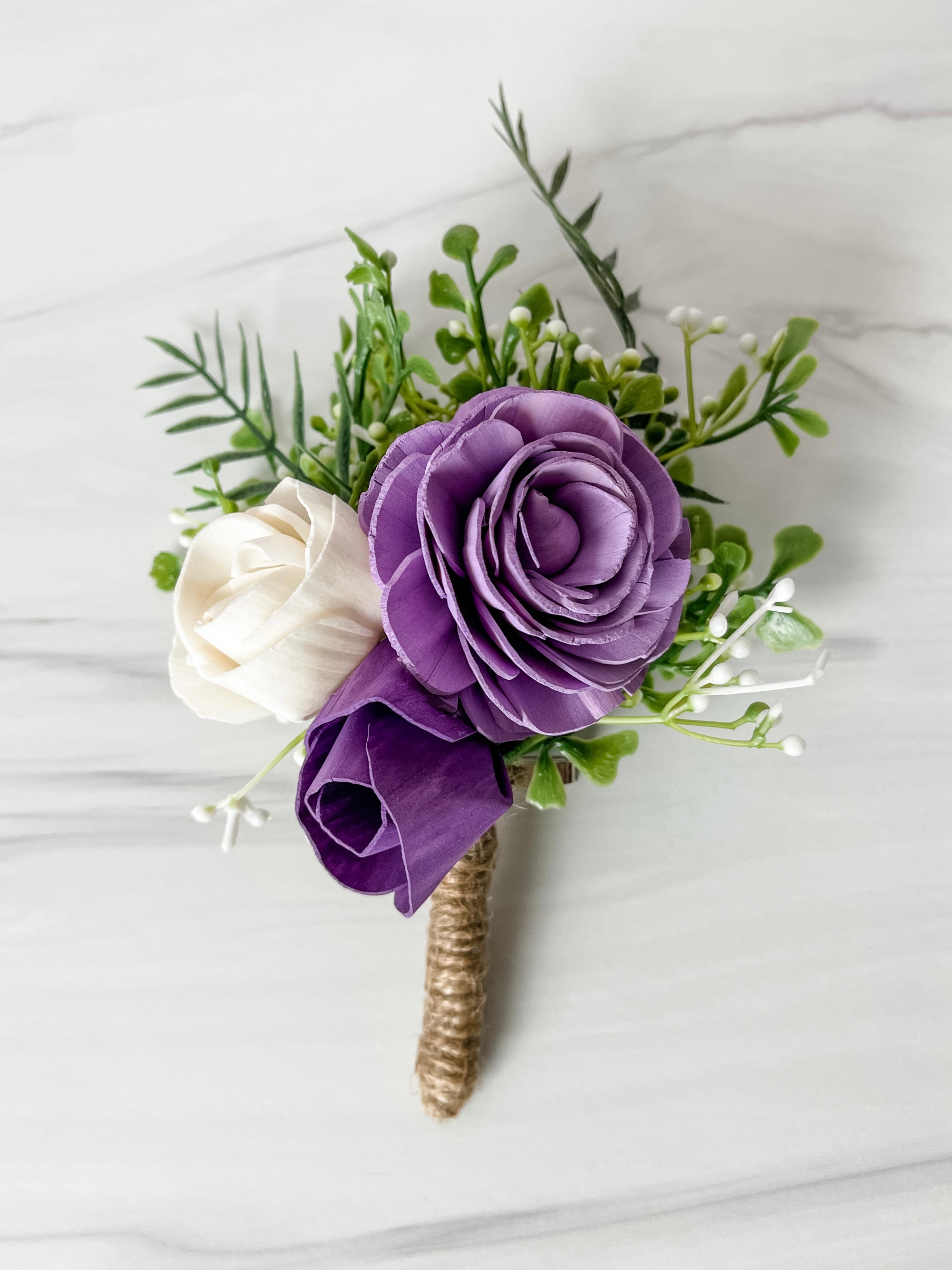 Floral boutonniere with purple and white flowers on a light background