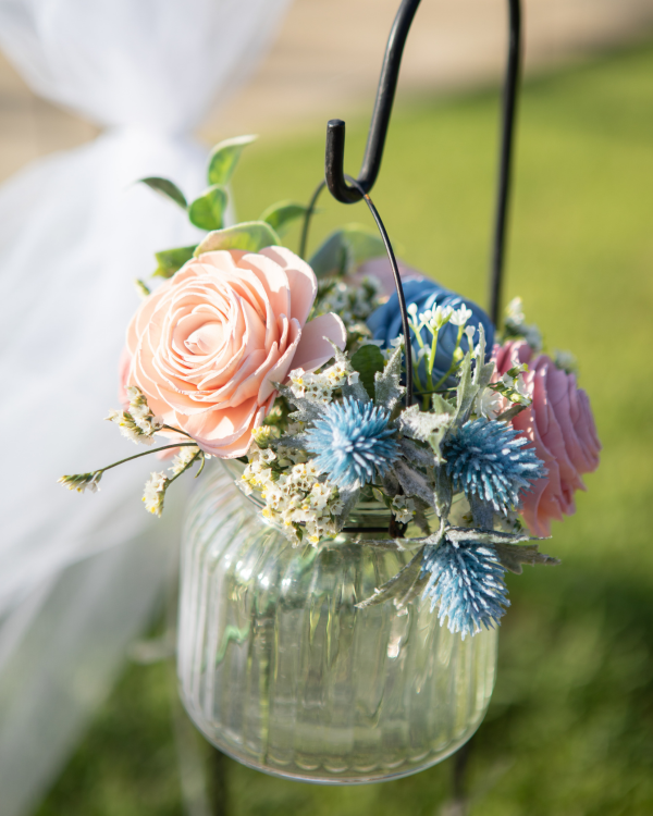 Hanging glass planter with pink and blue flowers on a blurred green background