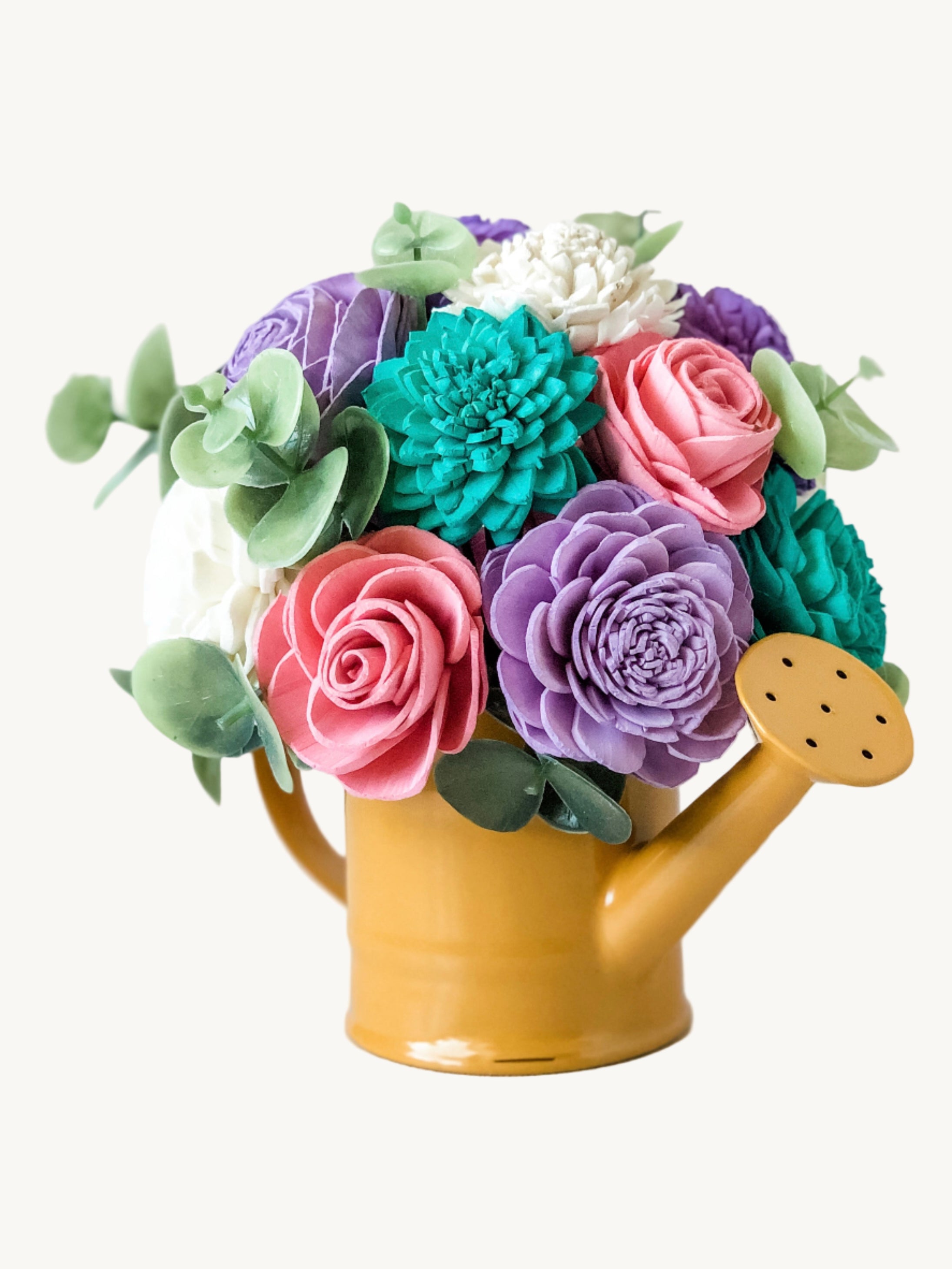 Colorful felt flower arrangement in a yellow watering can on a light background