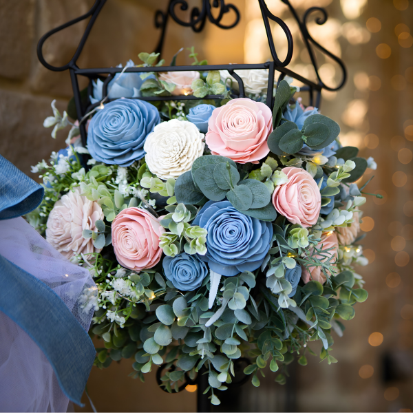 Decorative hanging basket with flowers and greenery against a blurred background